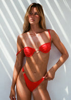 Woman wearing a red bikini against a white wall with shadow patterns